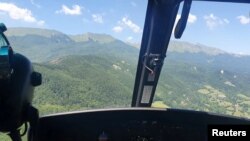 An Alpine Rescue helicopter flies over a helicopter crash site near Pievepelago, Italy, June 11, 2022.