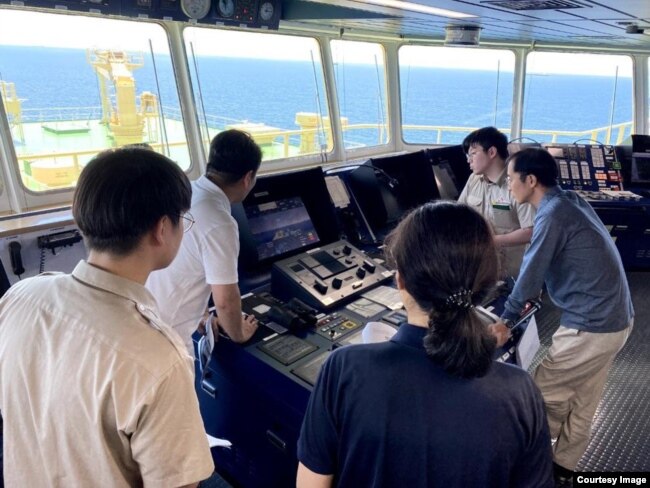 Crew members aboard the Prism Courage autonomous tanker monitor progress during a trip from a port in Texas to South Korea. (Image Credit: Avikus/SK Shipping)