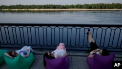 Women rest in front of the Dnieper River in Kyiv, Ukraine, June 10, 2022.