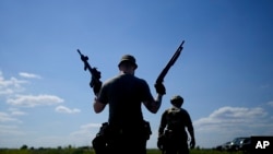 A civilian militia man holds a shotgun and a rifle during training at a shooting range in outskirts Kyiv, Ukraine, June 7, 2022.