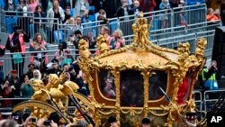 Kereta Gold State, yang membawa Elizabeth menuju Westminster Abbey 70 tahun lalu tampak dihiasi dengan hologram Ratu Elizabeth II di luar Istana Buckingham di London, Minggu 5 Juni 2022.