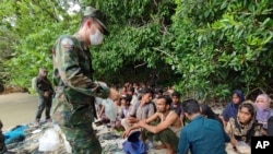 In this photo released by the Royal Thai Navy taken June 4, 2022, members of the Thai navy help Rohingya refugees found on Koh Dong Island in Satun province, southern Thailand.