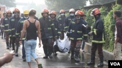 Firefighters are seen carrying a dead body. (Minhaz Uddin/VOA)