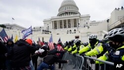 ARCHIVO - Insurrecciones violentas leales al presidente Donald Trump atraviesan una barrera policial en el Capitolio de Washington.