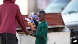 Un jeune garçon vend une miche de pain à Harare, Zimbabwe, le 23 mai 2022.