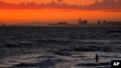FILE - A man wades into the ocean at sunset on June 22, 2021, in Newport Beach, Calif. The National Oceanic and Atmospheric Administration said June 3, 2022, that the amount of carbon dioxide in the atmosphere in May averaged 421 parts per million, more t