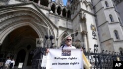 Protesters stand outside The Royal Court of Justice in London that will hear a legal challenge opposing the Home Office's new asylum deal with Rwanda, June 10, 2022.