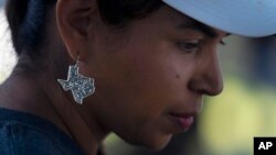 FILE - Ana Hernandez, a kindergarten teacher from Dilley, Texas, wears an earring in the shape of Texas to show support while visiting a memorial in Uvalde, Texas, June 3, 2022.