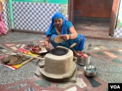 Poonam Devi does most of her cooking on a stove lit with woodfire though she has a cooking gas connection. (Anjana Pasricha/VOA)