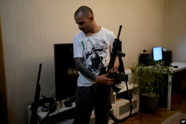 Viacheslav Drofa, known as Otoy, holds his rifle during an interview with The Associated Press at his home in Kyiv, Ukraine, Saturday, June 4, 2022. (AP Photo/Natacha Pisarenko)