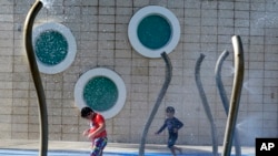Children play at a water park, June 13, 2022, in Miami Beach, Florida. More than 100 million Americans are being warned to stay indoors if possible as high temperatures and humidity settle over much of the South and Midwest.