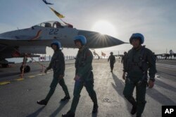 Pilot berjalan di dek kapal induk Shandong di pelabuhan Angkatan Laut di Sanya di Provinsi Hainan, China selatan. (Foto: via AP)