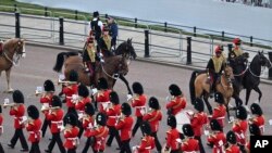 La Banda de los Guardias Galeses pasa junto a miembros de la Artillería Real a Caballo en camino al Desfile del Cumpleaños de la Reina, el miércoles 2 de junio de 2022, en Londres, en el primero de los cuatro días de celebraciones para conmemorar el Jubileo de Platino. Los eventos durante un largo fin de semana festivo en el Reino Unido están destinados a celebrar los 70 años de servicio de la monarca. (Paul Ellis/vía AP)