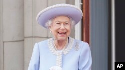 Ratu Elizabeth II tersenyum ketika menyaksikan acara perayaan platinum jubilee dari balkon Istana Buckingham pada 2 Juni 2022. (Foto: Pool via AP/Jonathan Brady)