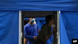 FILE - Residents line up for a throat swab at a coronavirus testing facility in Beijing, June 13, 2022. 