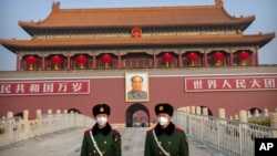 FILE: In this Jan. 27, 2020, file photo, paramilitary police wear face masks as they stand guard at Tiananmen Gate adjacent to Tiananmen Square in Beijing.