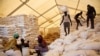 FILE: Men carry bags of food while women wait for their rations at a food distribution site in Pibor, South Sudan, June 25, 2012.