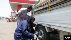 A picture taken May 26, 2022 shows Ghada Ahmed checking tire air at an auto quick service garage in Jeddah City. 