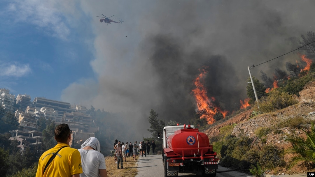 A wildfire burns near houses in the Panorama Voulas area, south of Athens, June 4, 2022. Whipped by gale-force winds, the fire blazed through vegetation, forcing residents to evacuate.