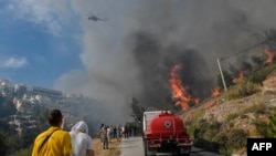A wildfire burns near houses in the Panorama Voulas area, south of Athens, June 4, 2022. Whipped by gale-force winds, the fire blazed through vegetation, forcing residents to evacuate.