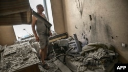 A man stands at his destroyed house as a rocket is nailed on a bed in the city of Lysychansk at the eastern Ukrainian region of Donbas on June 7, 2022.