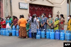 Warga berdiri di samping tabung Liquefied Petroleum Gas (LPG) yang kosong untuk memblokir jalan dalam aksi protes akibat kelangkaan bahan bakar dan gas untuk memasak di Kolombo, 7 Juni 2022. (Foto: AFP)