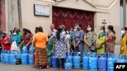 Warga Sri Lanka berdiri di samping tabung LPG kosong sebagai protes kekurangan bahan bakar dan gas untuk memasak di Kolombo pada 7 Juni 2022. (Foto: AFP)