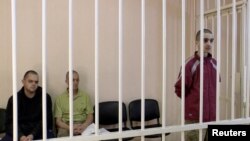 A still image, taken from video released June 8, 2022, by a court of the self-proclaimed Donetsk People's Republic, shows Britons Aiden Aslin, Shaun Pinner and Moroccan Saadoun Brahim in a courtroom cage at a location given as Donetsk, in a separatist-held part of Ukraine.