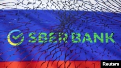 Логотип Сбербанка на фоне российского флага (иллюстрация REUTERS/Dado Ruvic)