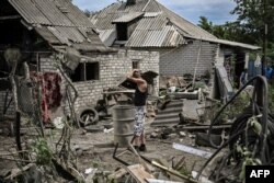 Maksym Katerin berdiri di halaman rumahnya yang rusak setelah ibu dan ayah tirinya tewas dalam penembakan di kota Lysychansk di wilayah Donbas, Ukraina timur. (Foto: AFP)