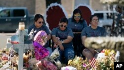 FILE - A group of teachers visiting from Dilley, Texas, view a memorial honoring the victims killed in last week's elementary school shooting in Uvalde, Texas, June 3, 2022.