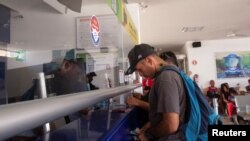Un migrante que salió de una caravana, luego de recibir sus documentos para cruzar el país, compra un boleto de autobús, en una estación de autobuses en Huixtla, México 10 de junio de 2022. REUTERS/Quetzalli Nicte-Ha