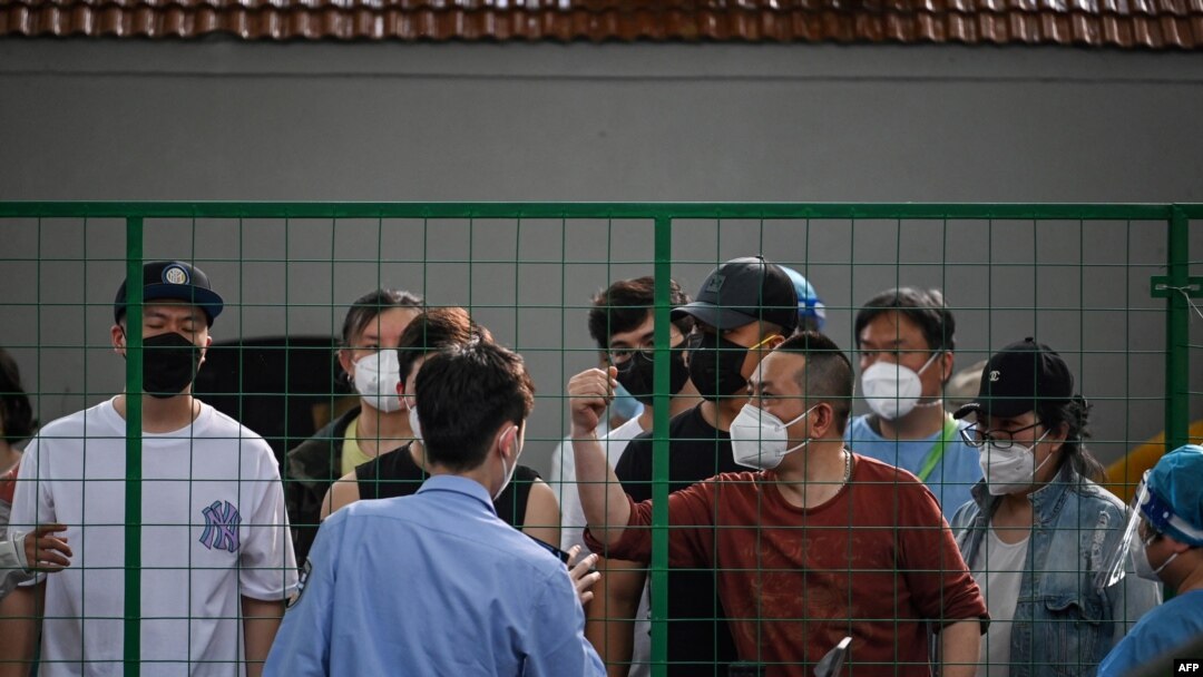 Angry residents confront officials from behind a fence erected in a neighborhood compound in the Xuhui district of Shanghai on June 6, 2022.