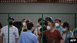 Angry residents confront officials from behind a fence erected in a neighborhood compound in the Xuhui district of Shanghai on June 6, 2022.