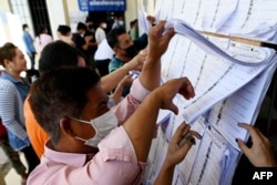 People look for their names in the voters' list at a polling station during local commune elections in Phnom Penh, Cambodia, June 5, 2022.