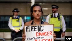A protester holds a placard as she stands outside the Home Office in central London on June 13, 2022, to demonstrate against the UK government's intention to deport asylum-seekers to Rwanda. The next day, Britain canceled its first deportation flight to Rwanda.