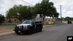 Two police vehicles are seen parked near a building at Robb Elementary School in Uvalde, Texas, June 2, 2022. The school was recently the site of a mass shooting.