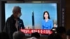 A man walks past a screen showing a news broadcast with file footage of a North Korean missile test, at a railway station in Seoul on June 5, 2022.