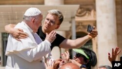 A man hugs Pope Francis to take a selfie after he had climbed on the popemobile at the end of the weekly general audience in St. Peter&#39;s Square at the Vatican.
