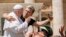 A man hugs Pope Francis to take a selfie after he had climbed on the popemobile at the end of the weekly general audience in St. Peter's Square at The Vatican.