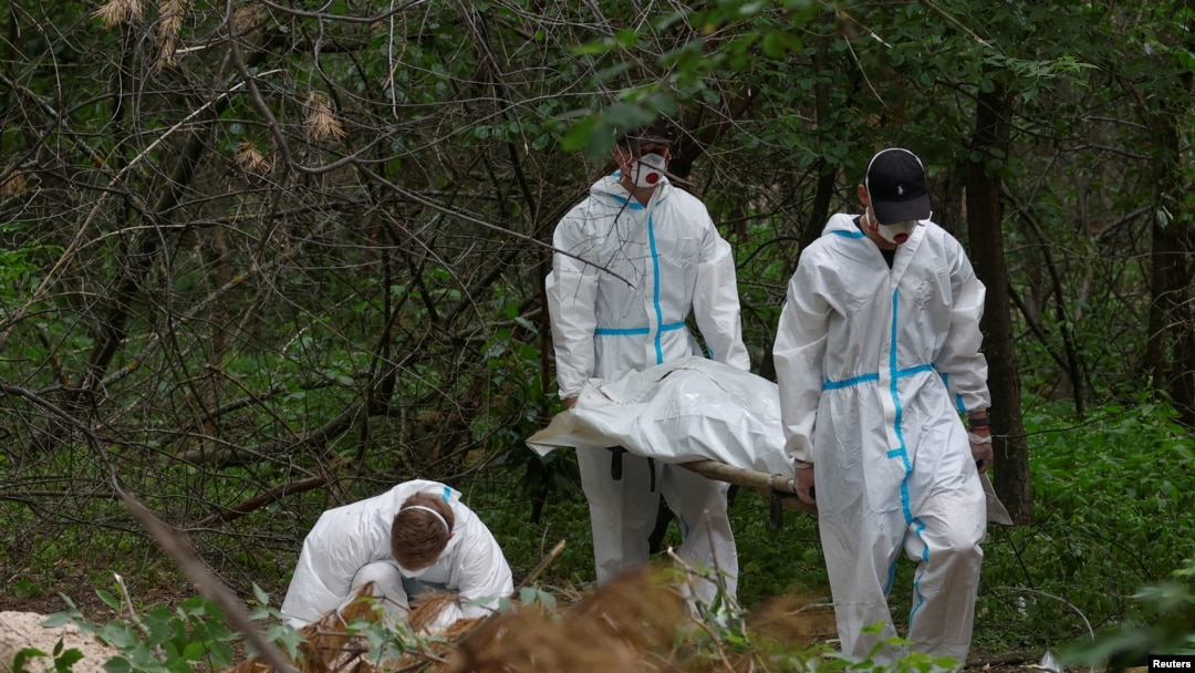 Forensic technicians carry a body of a person who, as Ukrainian police say, was killed and buried at a position of Russian troops during Russia's invasion, near the village of Vorzel in Bucha district, Kyiv region, Ukraine June 13, 2022.