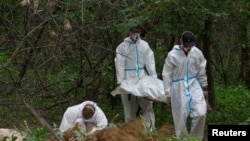 Forensic technicians carry a body of a person who, as Ukrainian police say, was killed and buried at a position of Russian troops during Russia's invasion, near the village of Vorzel in Bucha district, Kyiv region, Ukraine June 13, 2022.