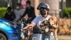 A woman rides a scooter with a dog in the Jing'an district of Shanghai on June 6, 2022, following the easing of COVID-19 restrictions in the city after a two-month lockdown. 