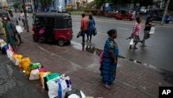 People place their canisters in line as they wait to buy kerosene oil outside a fuel station in Colombo, Sri Lanka, June 11, 2022.