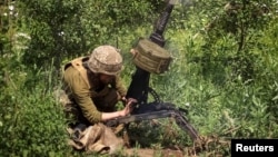 A Ukrainian service member shoots from an automatic grenade launcher at a position on the front line, amid Russia's attack on Ukraine, near Bakhmut, Donbas region, Ukraine, June 5, 2022. 