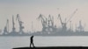 Архів. Чоловік гуляє з портовими кранами на задньому плані в торговому порту Маріуполя, Україна, 23 лютого 2022 р. (Фото AP/Сергій Гриць, файл)