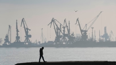 ARCHIVO - Un hombre camina con grúas portuarias de fondo, en el puerto comercial de Mariupol, Ucrania, el 23 de febrero de 2022. (Foto AP/Sergei Grits)