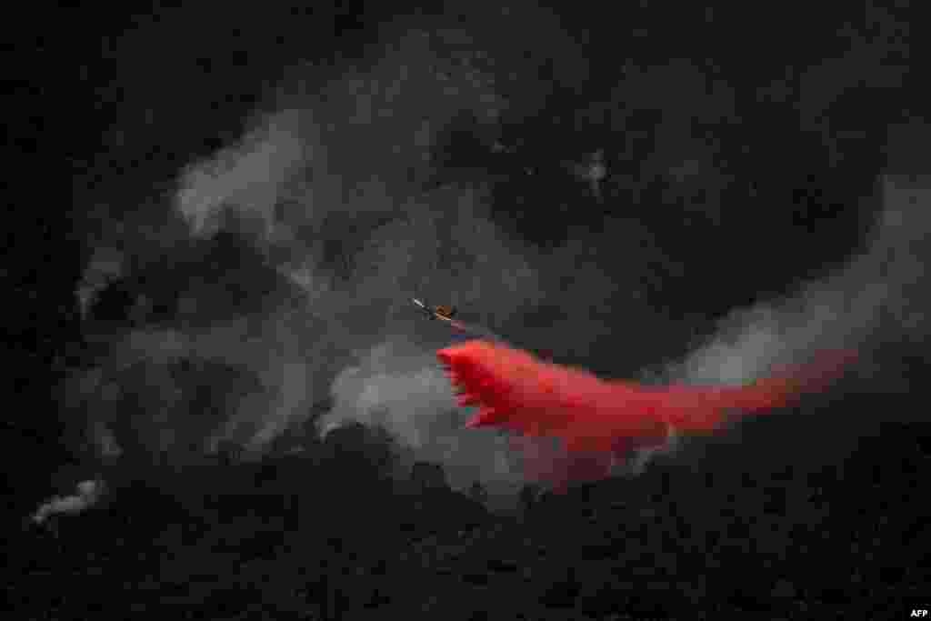 A plane, pictured from Benahavis, dumps fire retardant onto a wildfire at the Sierra Bermeja mountain range, province of Malaga, Spain.