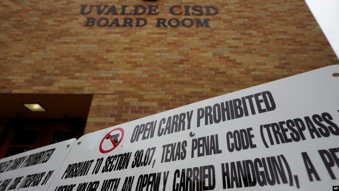 FILE - Signs prohibiting guns are displayed outside the Uvalde Consolidated Independent School District board room, where officials gave an update in the wake of the shooting at Robb Elementary, June 9, 2022, in Uvalde, Texas. 