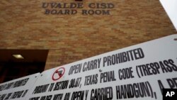 FILE - Signs prohibiting guns are displayed outside the Uvalde Consolidated Independent School District board room, where officials gave an update in the wake of the shooting at Robb Elementary, June 9, 2022, in Uvalde, Texas. 